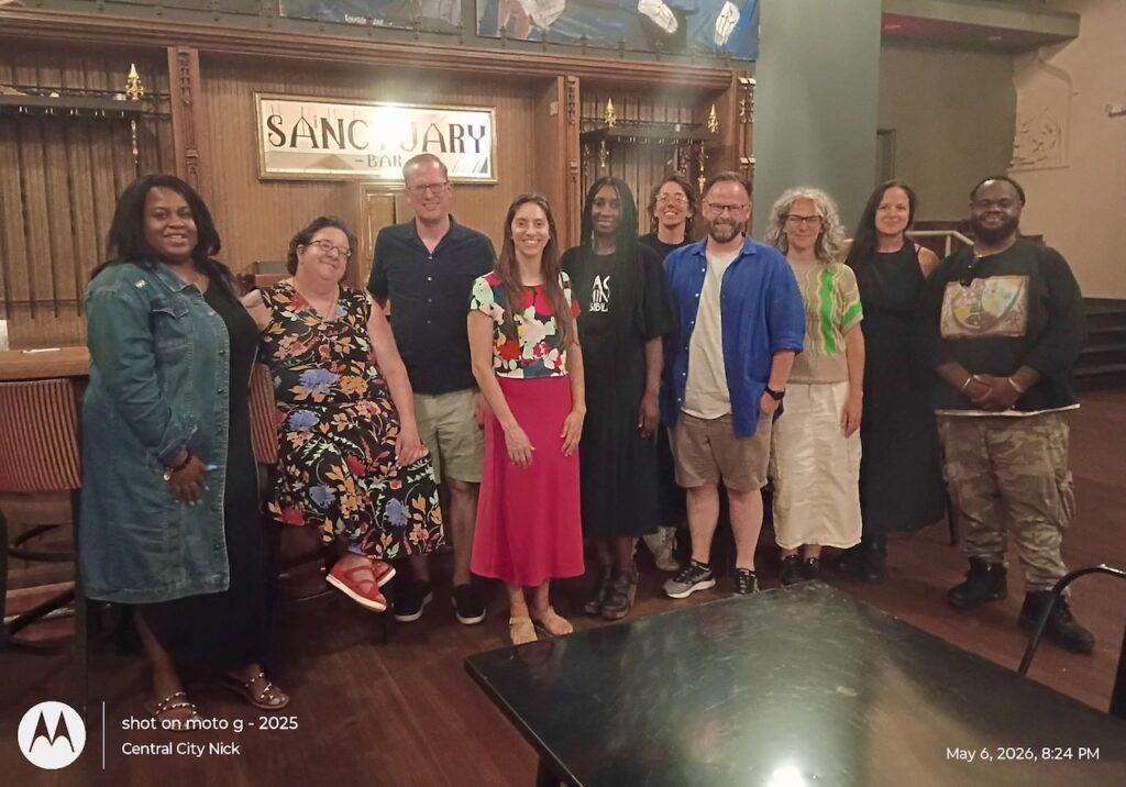 People from the Community Table event standing for a photo at the 'Sanctuary Bar' in the André Cailloux Center for Performing Arts and Cultural Justice.