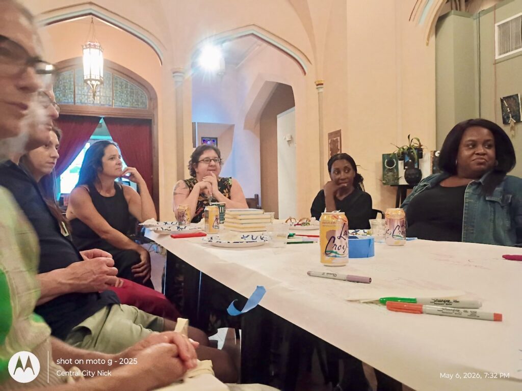 People sitting in conversation around a table that has been covered in paper and with pens.